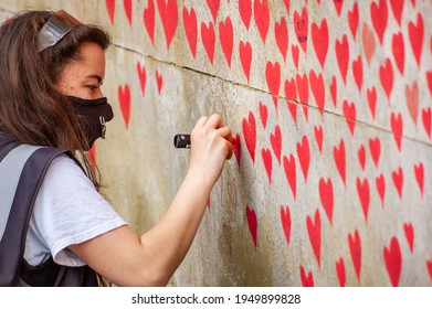 LONDON, ENGLAND- 31 March 2021: Volunteer Adding Love Hearts To The National Covid Memorial Wall