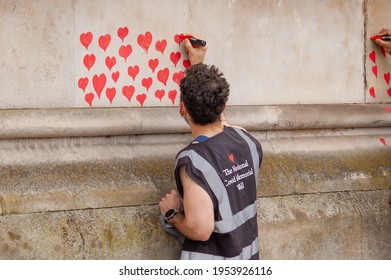 LONDON, ENGLAND- 31 March 2021: Volunteer Adding Hearts To The National Covid Memorial Wall