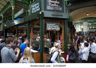 London, England - August 20, 2015: Staff can be seen working as people surround a seafood stall in Borough Market, London. The market has traded in Southwark, London for more than 250 years