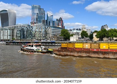 London, England - August 2021: Industrial barge passing under a bridge on the River Thames.