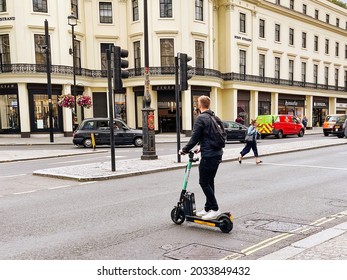 London, England - August 2021: Person Riding An Electric Scooter Across A Road In Central London