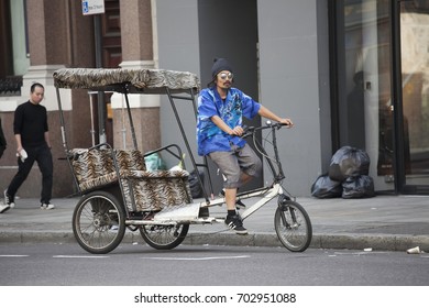 LONDON, ENGLAND - August 22, 2017 Rickshaw in a blue shirt and sunglasses rides around the city in search of customers
