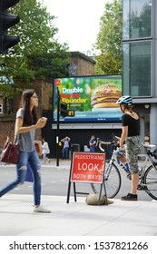 London / England - August 30 2019: A Digital Billboard Advert For A McDonald's Product Along Tottenham Court Road In London. Commuters Are Travelling Up And Down The Road.