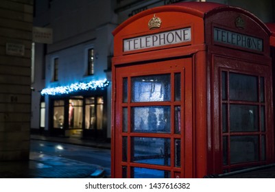 London, England - December 26 2015: Red Telephone Box In Empty Street At Night In West London