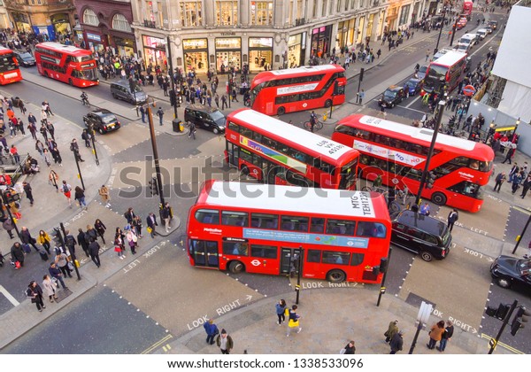 London, England - February\
26, 2019: Aerial image of Oxford circus and regent street junction\
with rush hour traffic of both pedestrians, cars and double deck\
buses.