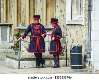 London, England – July 14, 2011: Two Guards Of Tower Of London And The King (beef Eater) In A Bright Red Uniform Of Tudor Era, Standing At Entrance Of Vault Of Royal Treasures, London, UK