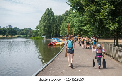 London, England -  July 2018 : Group Of Young Adepts Of Kayaking Carrying Their Oars To The Boats In Summer In Wimbledon Park