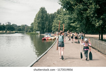 London, England -  July 2018 : Group Of Young Adepts Of Kayaking Carrying Their Oars To The Boats In Summer In Wimbledon Park