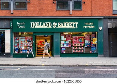 LONDON, ENGLAND - JULY 24, 2020:  Holland & Barrett Health Food Store At Holborn, London During The COVID-19 Pandemic With A Man Walking In Front Wearing A Face Mask - 061