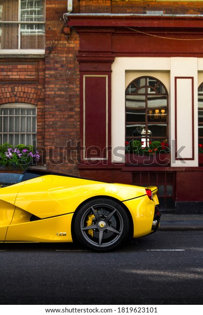 London, England - June 2018: rear side view of a\
yellow Ferrari LaFerrari Aperta supercar parked near a cafe in\
Mayfair area of central London.\
