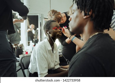 London, England - June 2019. London Fashion Week Men's, A Backstage Moment With A Black Model In Makeup Being Watched By A Black Male Model, 