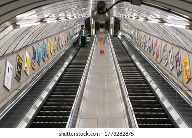 LONDON, ENGLAND - JUNE 8, 2020:  London Underground escalator with a man wearing a face mask observing social distancing measures during the COVID-19 pandemic - 025