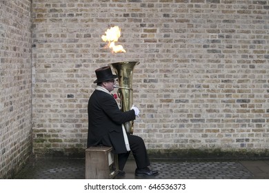 LONDON, ENGLAND - March 12, 2017 male actor is playing on a trumpet blowing a fire