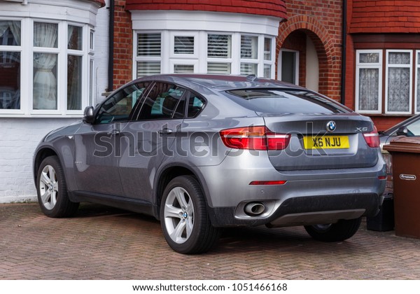 LONDON, ENGLAND\
- MARCH 6, 2017: A grey BMW X6 parked on a driveway of a terraced\
house in the  suburbs of\
London.