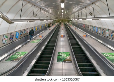 LONDON, ENGLAND - OCTOBER 23, 2020:  London Underground escalators at Holborn station during the rush hour with passengers wearing face masks and social distancing during the COVID-19 pandemic - 058