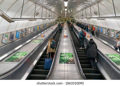 LONDON, ENGLAND - OCTOBER 23, 2020:  London Underground escalators during the rush hour commute with passengers wearing face masks and social distancing during the COVID-19 pandemic - 081