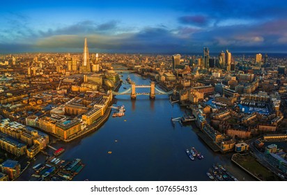 London, England - Panoramic aerial skyline view of London including iconic Tower Bridge with red double-decker bus, Tower of London, skyscrapers of Bank District at golden hour early in the morning