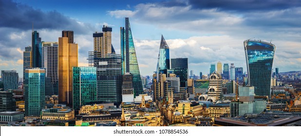 London, England - Panoramic skyline view of Bank and Canary Wharf, central London's leading financial districts with famous skyscrapers at golden hour sunset with blue sky and clouds - Shutterstock ID 1078854536