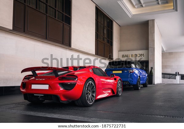 London, England - September 2019: red Porsche 918 Spyder\
and blue Range Rover Sport SVR parked at a luxury hotel in central\
London. 