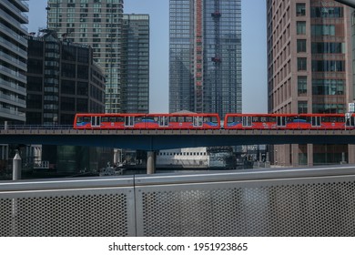 London, England, UK - 08 April 2021: DLR (Dockland Light Railway) Passing On A Bridge Above South Quay Canal In Canary Wharf. View From South Quay Footbridge.