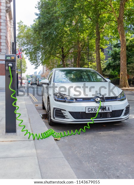 London, England, UK; 27th July 2018; White\
Volkswagen Golf GTE Plug-In Hybrid Electric Car Charging in a\
Central London Street.