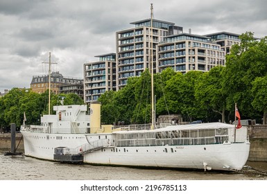 London, England, UK - July 6, 2022: From Thames River. Seahorse Hospitality White Boat, HQS Wellington, On North Shore With Green Foliage Of Victoria Gardens In Back Under. Gray Sky