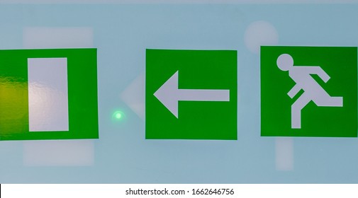 London, England, UK - March 02, 2020: A Neon Green Exit Sign Plate With A Man Figure And Arrow To The Door As An Instruction For Directions In Case Of An Emergency
