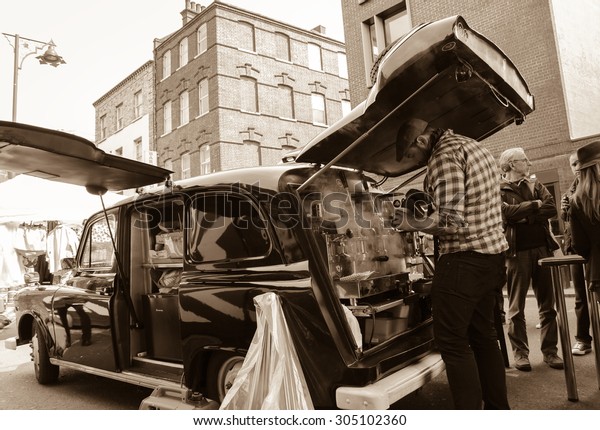 LONDON, ENGLAND, UK - MAY 4, 2014: Unidentified\
barista making coffee in mobile cafe (former old cab car) at Brick\
Lane market area.