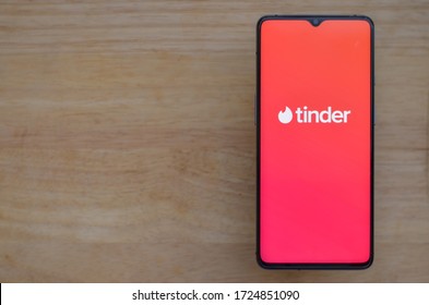 London, England, United Kingdom, 2020. Flat lay with wooden background and Tinder app logo on display on a smartphone screen. Tinder is an online social search and dating mobile app