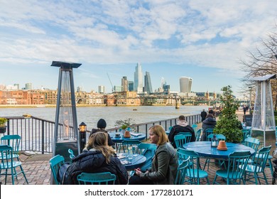 London February 2020. People relaxing in cafe by river thames skyline, London