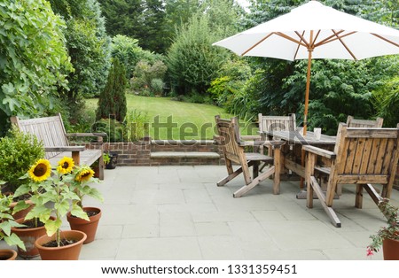 London garden in summer with patio, wooden garden furniture and a parasol or sun umbrella