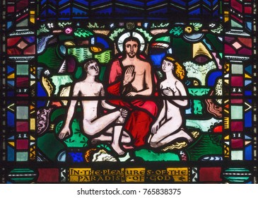 LONDON, GREAT BRITAIN - SEPTEMBER 16, 2017: The Adam and Eva in paradies with the Jesus on the stained glass in church St Etheldreda by Charles Blakeman (1953 - 1953).