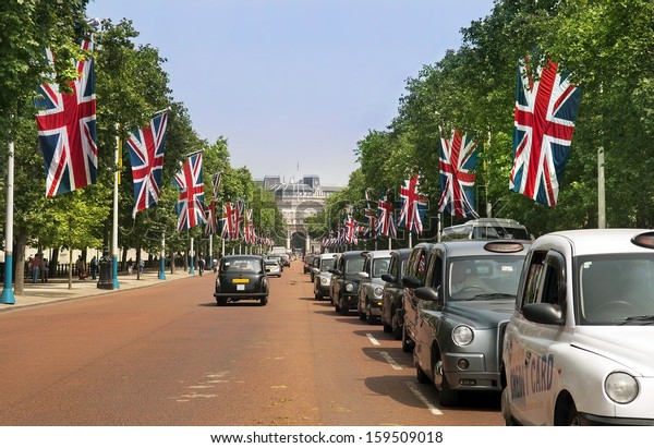 LONDON - July 15 :\
traditional London taxi, black cab on the street decorated with\
british flags and leading to the Mall with Admiralty Arch , on July\
15, 2013 in London, UK.