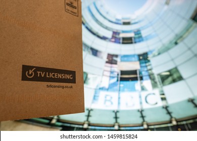 LONDON- JULY, 2019: TV Licence envelope against an image of the BBC headquarters. The UK government licence fee needed to watch live television