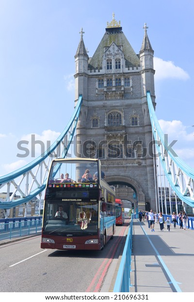 LONDON - JUNE 01, 2014: open\
top London Bus travels across the Tower Bridge in London. The Tower\
Bridge is a suspension bridge with a total length of 244\
metres.