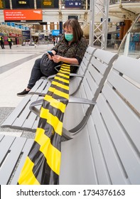 London, Liverpool Street Train Station, UK.  May 16th 2020: A Female Commuter Waits Patiently On A Concourse Public Seat, Taped Off For Crowd Control And Social Distancing. Covid-19 Guidance Measures.