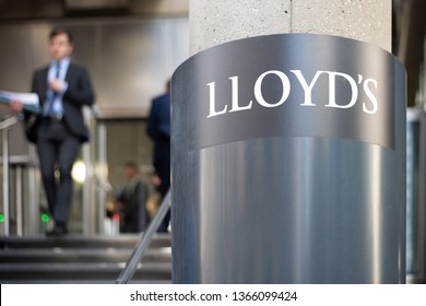 London, London/UK - April 10 2019: City worker in the background is seen leaving the Lloyds building. Sign for Lloyds is sharp, whereas city worker is blurred for effect. 