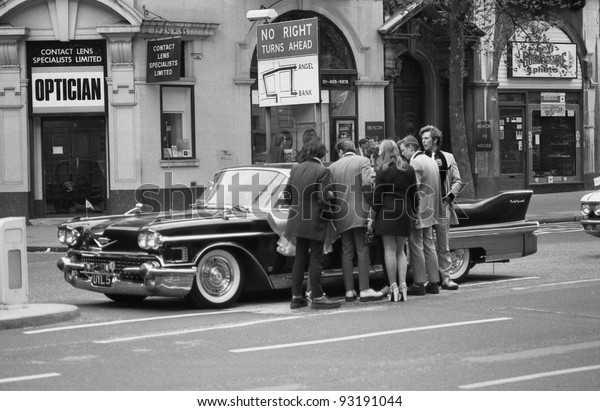 LONDON - MAY 15: Music fans admire a vintage\
American car during  the Rock \'n\' Roll Radio Campaign march on May\
15, 1976 in London, England. The campaign aims to get more Rock \'n\'\
Roll music played on\
radio.