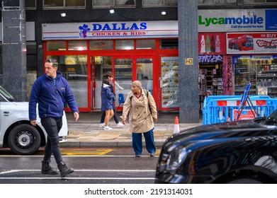 LONDON - May 20, 2022: People Crossing Busy London Street Between Taxis