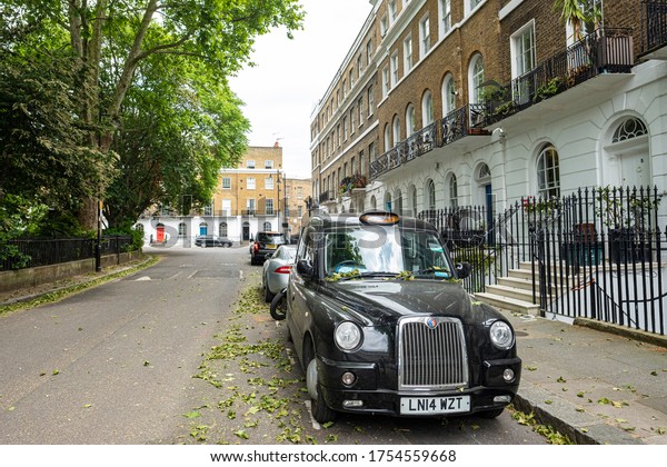 LONDON- MAY, 2020: A black London taxi\
parked on attractive London residential\
street