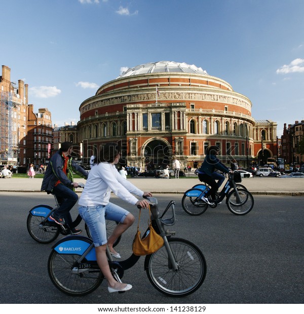 LONDON - MAY 26: Tourists on rental bike passing by\
Royal Albert Hall on May 26, 2013 in London, UK. London\'s bicycle\
sharing scheme launched with 6000 bikes on 2010 to help ease\
traffic congestion. 