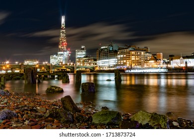 London Night Time City Scape From The North Bank Of The River Thames At Low Tide.