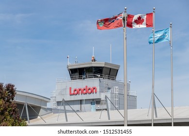 London, ON, Canada - September 19, 2019: London International Airport (YXU) Air Traffic Control Tower Above The Airport's Main Terminal With A Text Sign That Reads London And Flags Waving In Front.