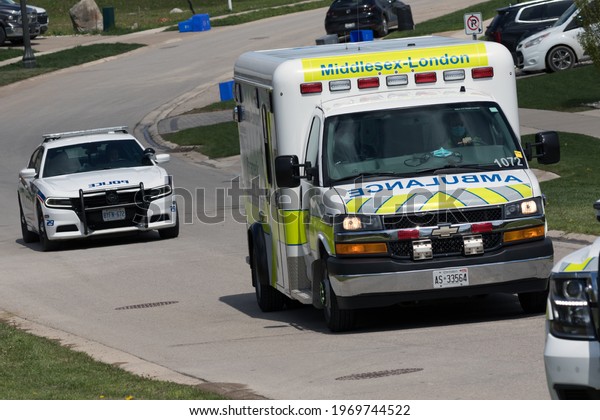 London,\
Ontario  Canada - May 07 2021:  Ambulance and a police cruiser on\
scene for a call in London, Ontario,\
Canada.