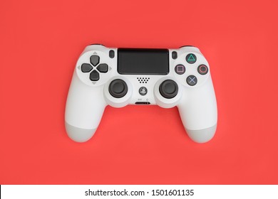 LONDON - SEPTEMBER 06, 2019: Video games PlayStation white gaming controller isolated on red color background top view
