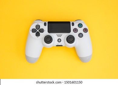 LONDON - SEPTEMBER 06, 2019: Video games PlayStation white gaming controller isolated on yellow color background top view