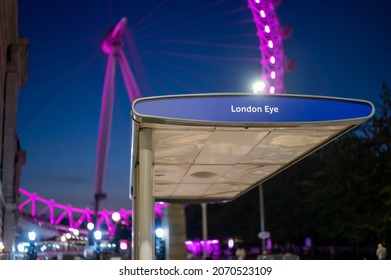 LONDON - SEPTEMBER 14, 2021: London Eye Bus Shelter With The Wheel Out Of Focus And Illuminated At Night In The Background