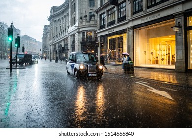 LONDON- SEPTEMBER, 2019: Wet And Moody London Street With A Black Taxi Cab Driving In Torrential Rain On Regent Street