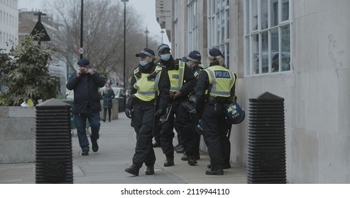 London, UK - 01 22 2022: A group of male and female met police officers wearing face masks, standing on the sidewalk at Portland Place, in preparation for the ‘World Wide Rally For Freedom’.