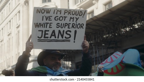 London, UK - 03 19 2022: Man Walking On Regent Street Holding Sign At Protest, ‘Now I’m Proud! I’ve Got My White Superior Jeans!’, At The Yearly ‘March Against Racism’, ‘UN Anti Racism Day’.